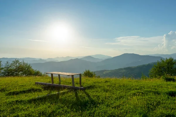 Wood bench on green meadow on sunrise, Apetska mountain, Carpathians mountains landscapes.