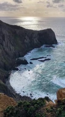 Kayalık uçurum kıyıları ve dalgaların üzerine çöktüğü cennet manzarası. Sörfçü Praia do Castelejo 'daki kayalar Sagres yakınlarında. Portekiz 'in güneyindeki Algarve bölgesinin Batı Atlantik kıyıları.