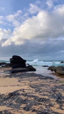 Kayalık uçurum kıyıları ve dalgaların üzerine çöktüğü cennet manzarası. Sörfçü Praia do Castelejo 'daki kayalar Sagres yakınlarında. Portekiz 'in güneyindeki Algarve bölgesinin Batı Atlantik kıyıları.