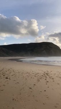 Kayalık uçurum kıyıları ve dalgaların üzerine çöktüğü cennet manzarası. Sörfçü Praia do Castelejo 'daki kayalar Sagres yakınlarında. Portekiz 'in güneyindeki Algarve bölgesinin Batı Atlantik kıyıları.