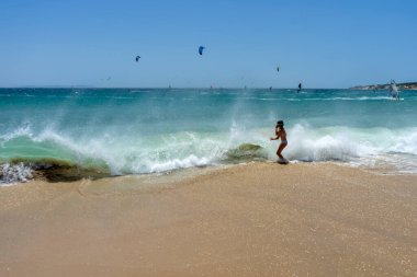 TARIFA, İspanya - 17 Haziran 2023: Çocuklar 17 Haziran 2023 tarihinde İspanya 'nın Tarifa kentindeki Gibraltar Boğazı Valdevaqueros plajında dalgaların tadını çıkarıyorlar.