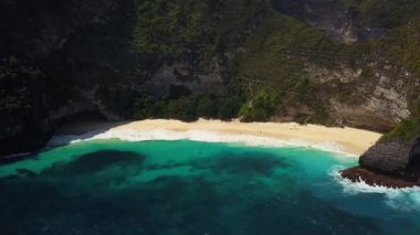 İnsansız hava aracı görüntüleri. Okyanustaki tropik ada. Temiz turkuaz su kayalara ve adanın kumlu sahillerine çarpar. Nusa Penida 'daki Kelingking plajında uçuşu çok güzel. Seyahat kavramı