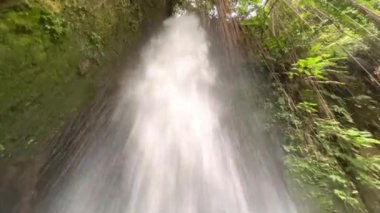 Çalkantılı suyla güçlü Sumampan şelalesine yakın çekim. Uçurumdan kristal berrak buzul akıntısı düşüyor. Aşağıdan bak. 4K Video. Ubud, Bali, Endonezya.