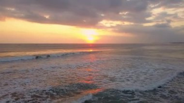 Gün batımında okyanus dalgalarını gösteren drone görüntüsü. Endonezya, Asya 'daki Bali Adası' ndaki tropik cennet beldesinde günbatımı dalgalı deniz manzarası. Sinema robotu yumuşak güneş ışığında doğanın manzarasını çekti.
