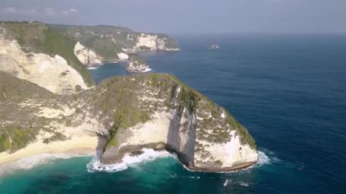 Nusa Penida Adası 'ndaki Kelingking Sahili' nin tepeden aşağıya insansız hava aracı manzarası masmavi dalgaları ve dağları olan güzel okyanus. Bali, Endonezya. İHA atışını kıyıdan yukarı kaldır. Tyrannosaurus Rex dinozor uçurumu.
