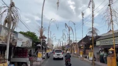 Yol boyunca Penjor. Her iki tarafa da yayılmış hareket halindeki bir araçtan yola bakan Balili Hindu dini refah sembolü Penjor. Bali, Endonezya, 4 Eylül 2022