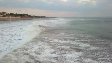 4K hava aracı Bali adasındaki okyanus sahili kıyı şeridinde vuruldu. Hint Okyanusu 'nda dalgalar geliyor ve sahilde güzel evler var..