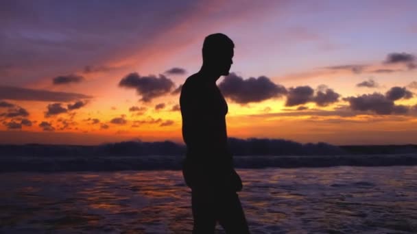 Силуэт Человека Идущего Вдоль Океана Фоне Яркого Огненного Многоцветного Заката — стоковое видео