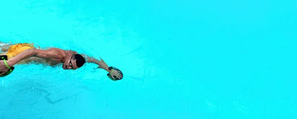 男はプールで運動している 青い澄んだ水の中で水泳ゴーグルを着用し 手のパドルを使用して好気性の男性水泳のトップビュー 広い旗 旗の端に男 — ストック写真