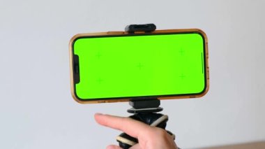 Yeşil ekran telefon. Tripoda yerleştirilmiş hareket takip işaretleyicileri ile akıllı telefon ekranını araklayan yakın plan. Çevrimiçi öğrenme, kişisel gelişim, kurslar, sosyal medya okuma