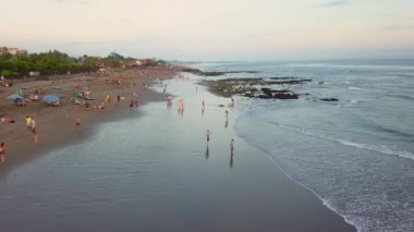 İnsansız hava aracı görüntüleri bir okyanus sahilinde uçuyor ve Endonezya 'daki Bali adasında gün batımını izleyen bir kalabalık var. Seyahat ve doğa. 4 bin. Bali, Endonezya, 11.09.2022