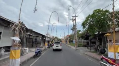 Yol boyunca Penjor. Hareket halindeki bir araçtan yola bakmak, her iki tarafta refahın sembolüdür - Penjor. Kamera iki yönlü bir yolda arabayı takip ediyor. Bali, Endonezya, 4 Eylül 2022