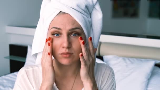 一个年轻女子的画像 她看着相机 触摸着她的脸 头上戴着毛巾 穿着浴衣 面部和身体护理 美容和抗衰老治疗的概念 — 图库视频影像