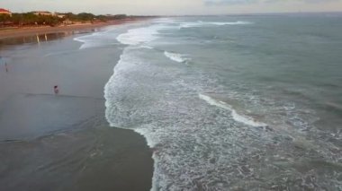 Hint Okyanusu 'nda dalgalar koparken Sunset' in insansız hava aracı görüntüleri. Okyanus dalgaları üzerinde gün batımı kum plajlarını yıkar. Hava günbatımı. Sahildeki insanlar, deniz manzarası. Cennet Bali Adası, Endonezya, Asya deniz koyunda