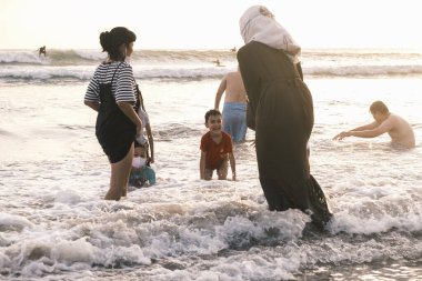 Bir grup insan ve çocuk elbiseleriyle denizde yüzüyor. Endonezya, Bali, 03.07.2022