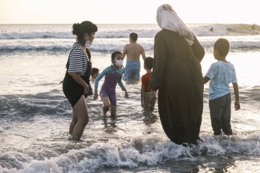 Bir grup insan ve çocuk elbiseleriyle denizde yüzüyor. Endonezya, Bali, 03.07.2022