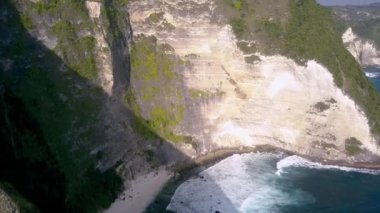 Bali, Endonezya 'daki ünlü Kelingking Sahili ve Nusa Penida kayalıklarının dramatik hava aracı görüntüleri.