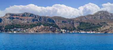 Yunanistan 'ın Dodekanisos kentindeki Kastellorizo adasındaki kayalıklarda geleneksel renkli deniz evleri ve Yunan bayrağı