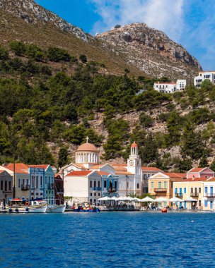 Yunanistan 'ın Dodekanisos kentindeki Kastellorizo adasındaki kayalıklarda geleneksel renkli deniz evleri ve Yunan bayrağı