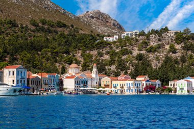Yunanistan 'ın Dodekanisos kentindeki Kastellorizo adasındaki kayalıklarda geleneksel renkli deniz evleri ve Yunan bayrağı