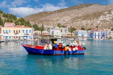 Yunanistan 'ın Dodekanisos kentindeki Kastellorizo adasındaki kayalıklarda geleneksel renkli deniz evleri ve Yunan bayrağı