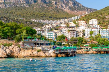 Kas, Antalya, Türkiye - 7 Ağustos 2024: Arka planda kaya ve kas kenti üzerine kurulan tatil beldesi ve restoran