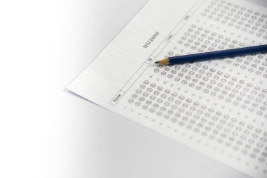 Mavi bir kalemi tutan bir eli gösteriyor ve bir sınav kağıdına 