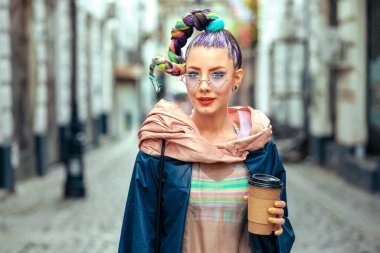 Cool funky young girl with piercing and crazy hair enjoy takeaway coffee on street, Hipster woman with trendy colorful avant-garde look having fun outdoor clipart