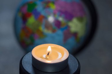 Dünyanın arka planında yanan bir mum. Ukrayna 'da savaş nedeniyle elektrik kesintisi