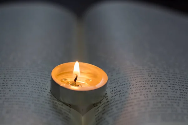 本の上でろうそくを燃やす ウクライナでの戦争による停電 — ストック写真
