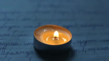 Okul defterinde yanan bir mum. Ukrayna 'daki savaştan dolayı karartma