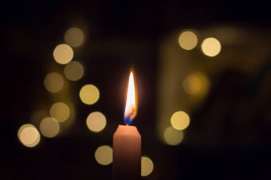 Rafların arkasında kitaplarla yanan mum. Ukrayna 'da savaş nedeniyle elektrik kesintisi