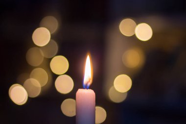 Rafların arkasında kitaplarla yanan mum. Ukrayna 'da savaş nedeniyle elektrik kesintisi