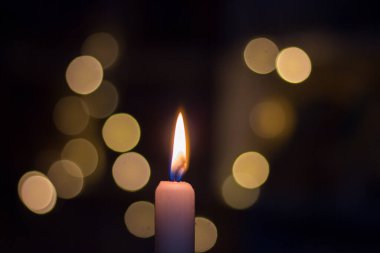 Rafların arkasında kitaplarla yanan mum. Ukrayna 'da savaş nedeniyle elektrik kesintisi