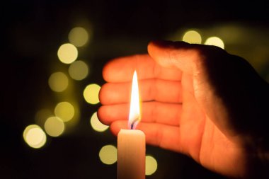 El, karanlık bir odada mum ateşini kapatır. Ukrayna 'da savaş nedeniyle elektrik kesintisi