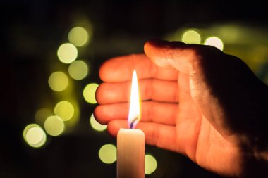 El, karanlık bir odada mum ateşini kapatır. Ukrayna 'da savaş nedeniyle elektrik kesintisi