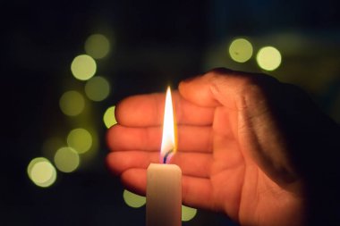 El, karanlık bir odada mum ateşini kapatır. Ukrayna 'da savaş nedeniyle elektrik kesintisi