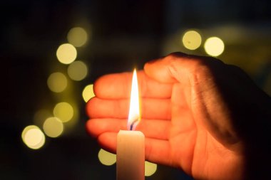 El, karanlık bir odada mum ateşini kapatır. Ukrayna 'da savaş nedeniyle elektrik kesintisi