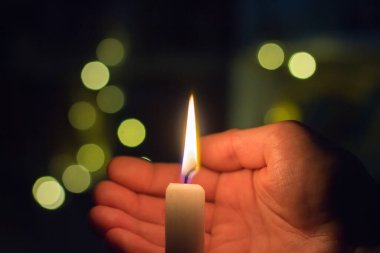 El, karanlık bir odada mum ateşini kapatır. Ukrayna 'da savaş nedeniyle elektrik kesintisi