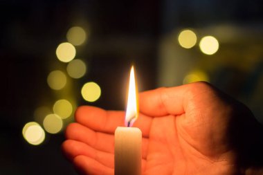 El, karanlık bir odada mum ateşini kapatır. Ukrayna 'da savaş nedeniyle elektrik kesintisi