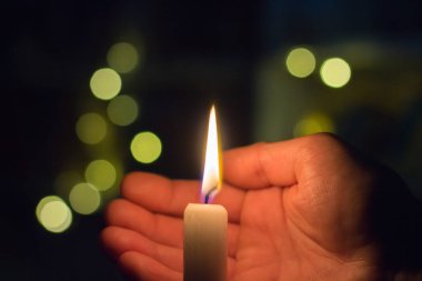 El, karanlık bir odada mum ateşini kapatır. Ukrayna 'da savaş nedeniyle elektrik kesintisi