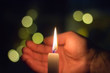 El, karanlık bir odada mum ateşini kapatır. Ukrayna 'da savaş nedeniyle elektrik kesintisi