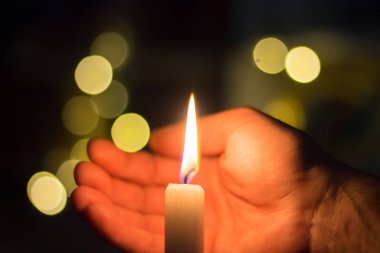 El, karanlık bir odada mum ateşini kapatır. Ukrayna 'da savaş nedeniyle elektrik kesintisi