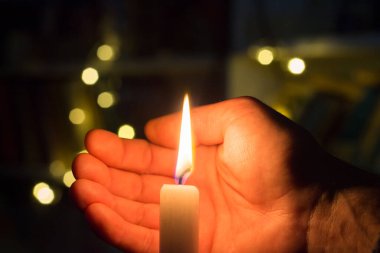 El, karanlık bir odada mum ateşini kapatır. Ukrayna 'da savaş nedeniyle elektrik kesintisi