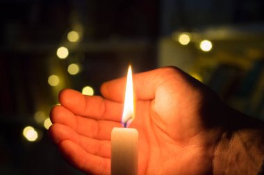 El, karanlık bir odada mum ateşini kapatır. Ukrayna 'da savaş nedeniyle elektrik kesintisi