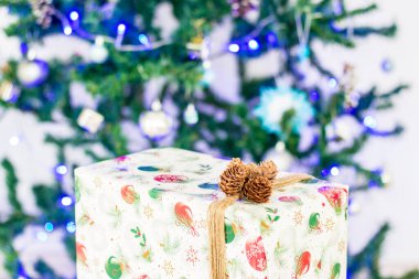 Yılbaşı hediyesi bir yılbaşı ağacının arka planındaki bir kutuda.