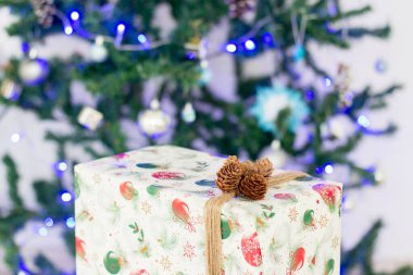 Yılbaşı hediyesi bir yılbaşı ağacının arka planındaki bir kutuda.