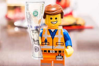 Slovakya. Sala. 01/01/2023. Yüzünde neşeli bir ifadeyle bir LEGO çalışanının elindeki banknot Lego 2 Emmet Smile 'ın ellerinde para..