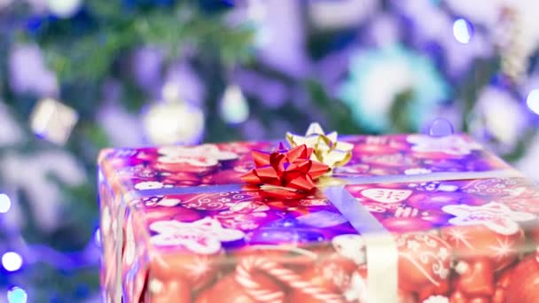 Újévi Ajándék Egy Dobozban Háttérben Egy Karácsonyfa Megvilágítással — Stock videók