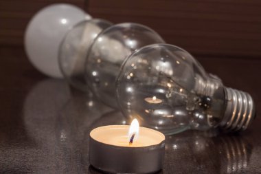Burning candle on the background of light bulbs. Blackout due to war in Ukraine